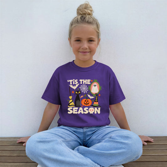 Girl wearing a purple Tis The Season Halloween youth tee with a black cat, jack-o'-lantern and ghost